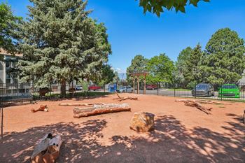 A playground with a large log and a tree in the background